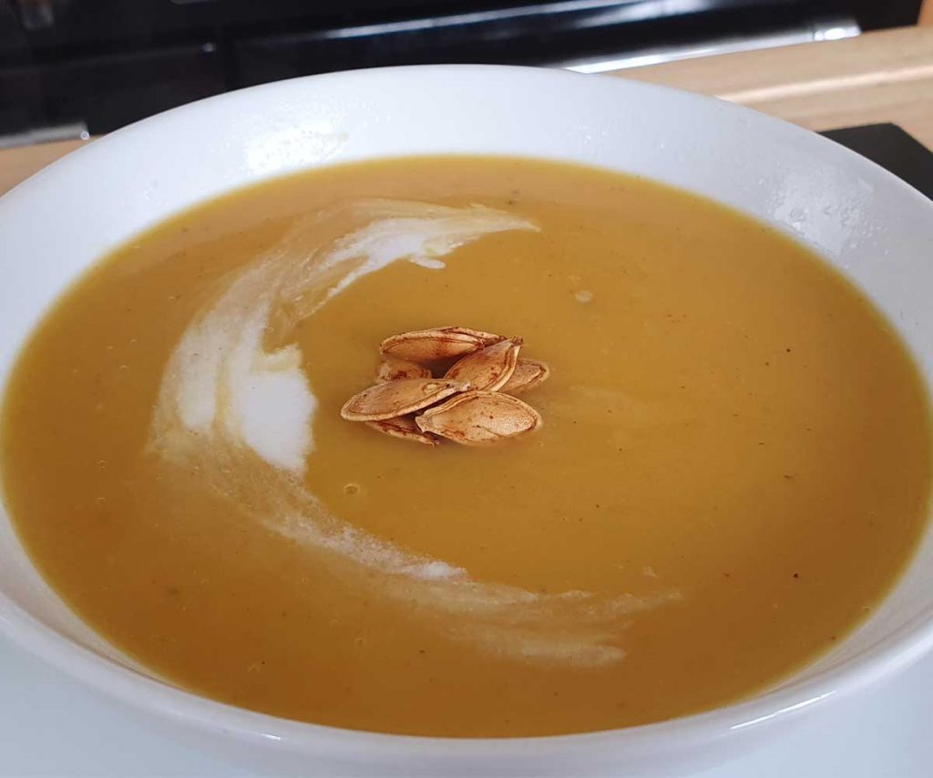 A bowl of pumpkin soup decorated with pumpkin seeds